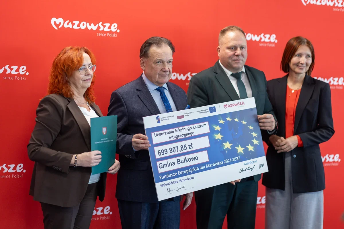 Trzy osoby pozują z symbolicznym czekiem na utworzenie lokalnego centrum integracyjnego w Gminie Bulkowo.