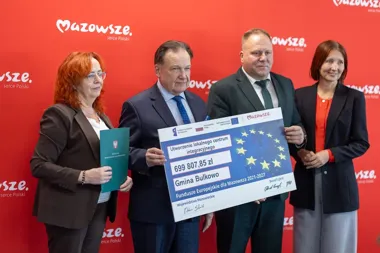 Trzy osoby pozują z symbolicznym czekiem na utworzenie lokalnego centrum integracyjnego w Gminie Bulkowo.